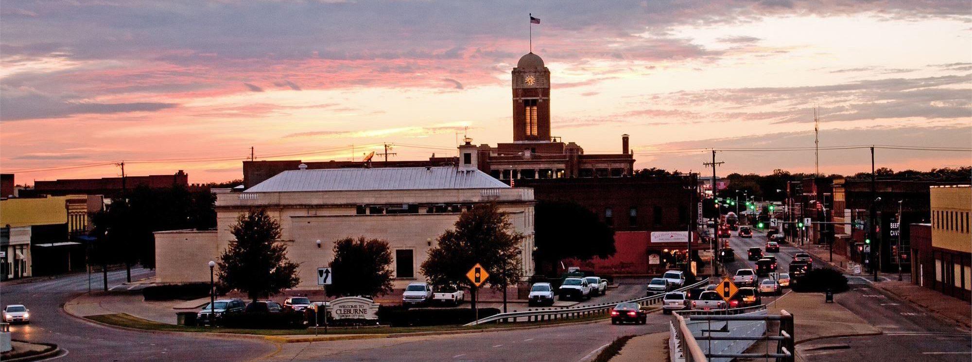 downtown Cleburne, Texas during sunset with cars driving